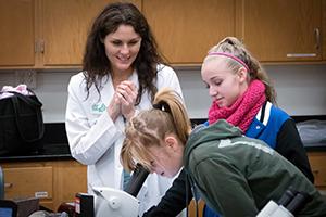 Photo of teacher and female students with microscope